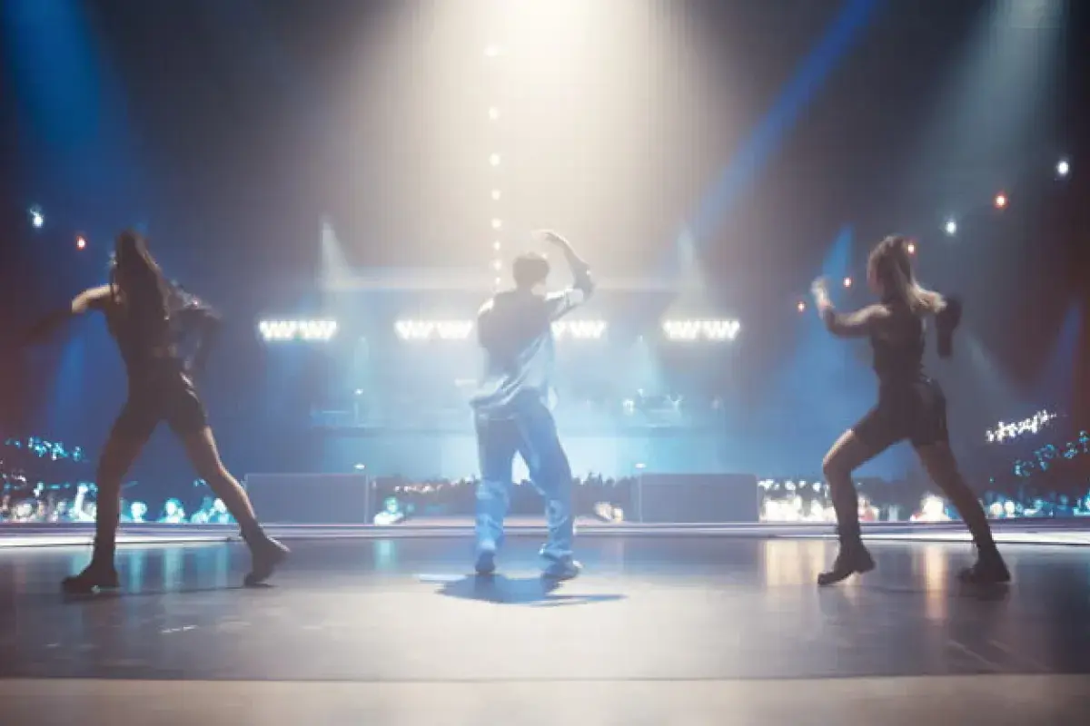 K-pop idols performing synchronized choreography on stage under colorful lights