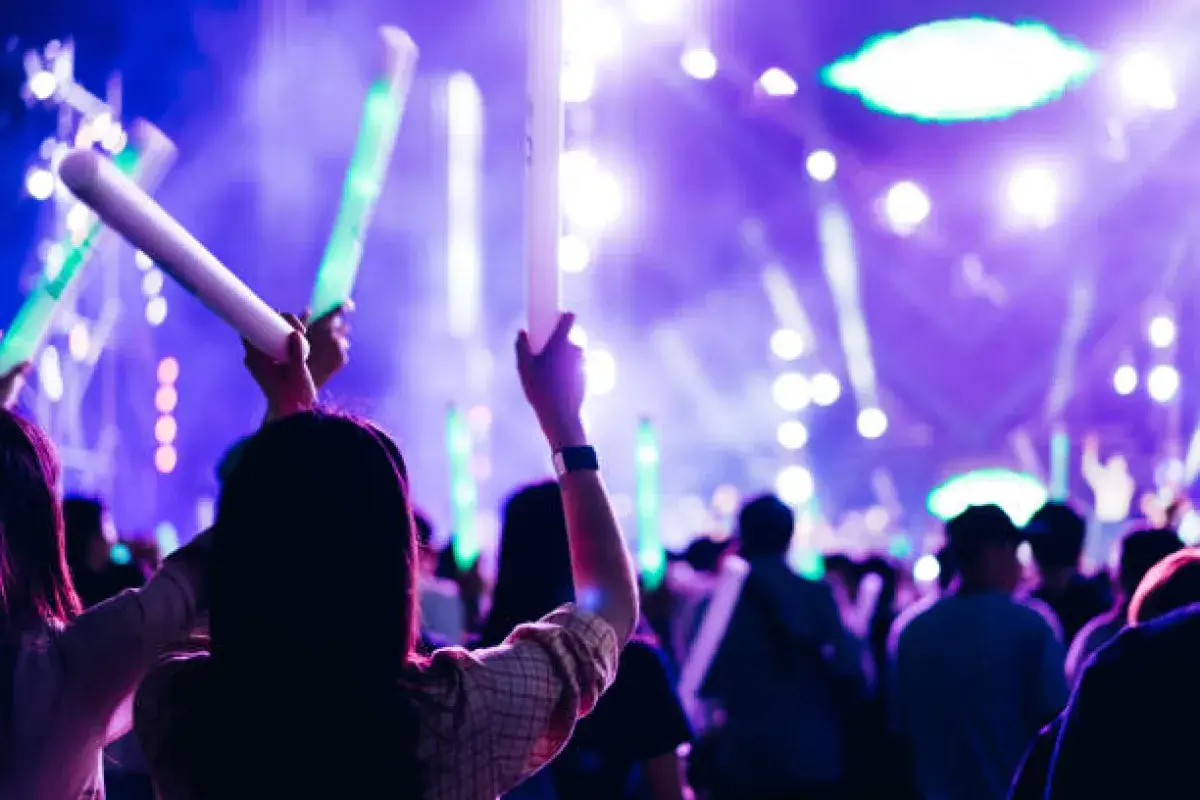 K-pop fans holding official lightsticks and banners at a live concert
