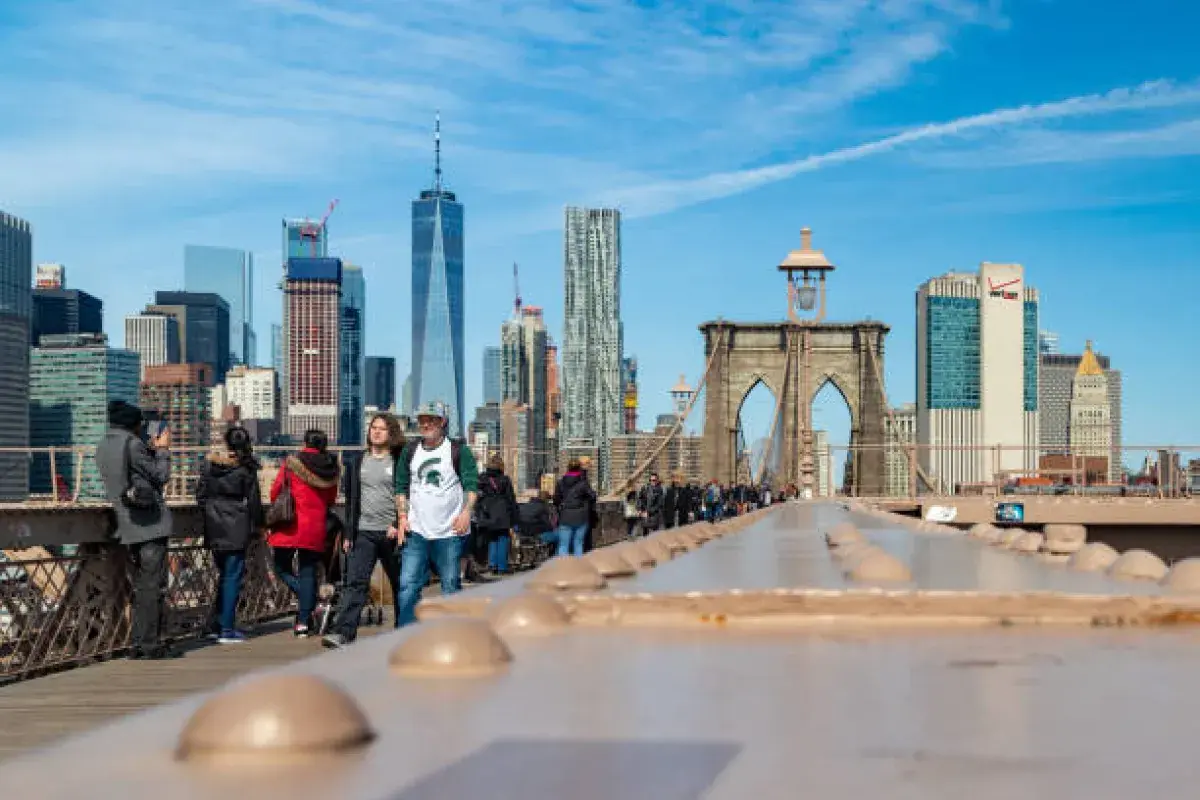 People walking on Brooklyn Bridge with city skyline in the background