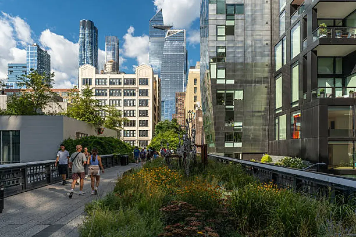 Visitors walking along the High Line park with views of Manhattan buildings