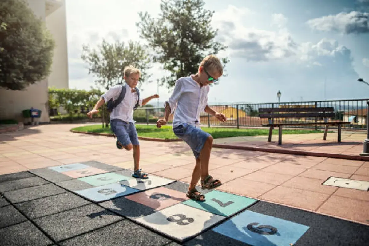 Kids playing hopscotch and running in a playground