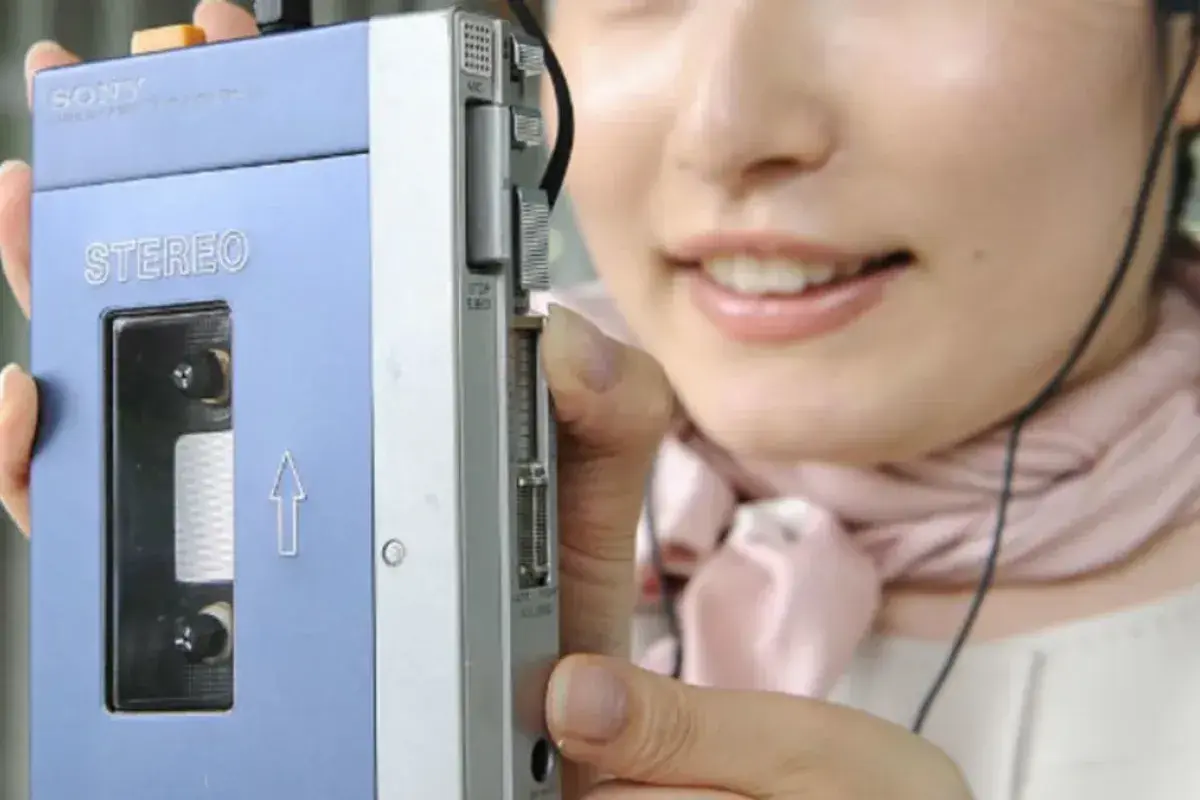 Person using a Sony Walkman with headphones while walking outdoors in 1979