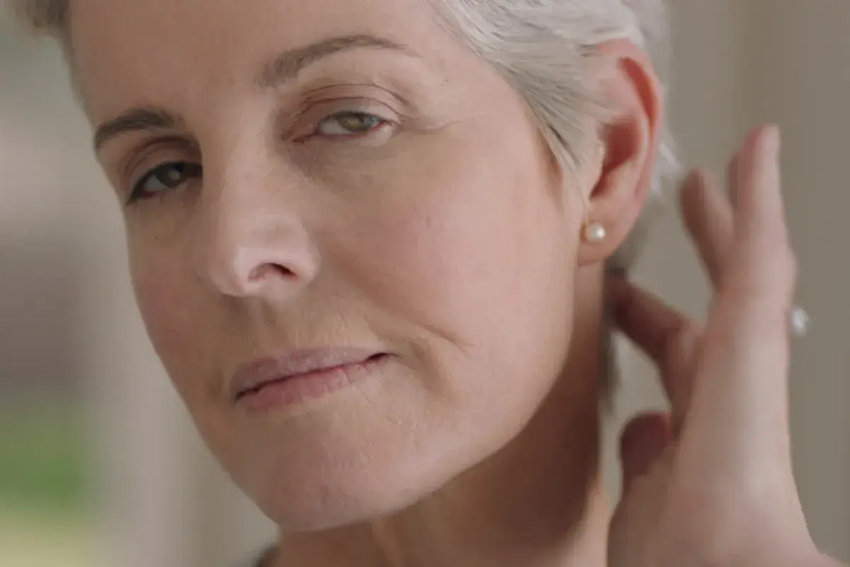 portrait beautiful mature woman looking in mirror at perfect healthy skin touching face with hands enjoying smooth natural complexion with anti aging skincare getting ready at home beauty