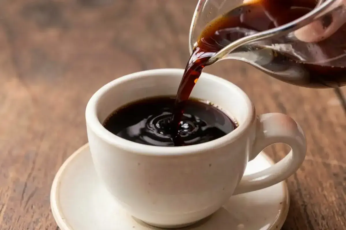 Freshly brewed black tea pouring into ceramic cup