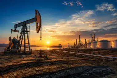 Oil pumpjack and refinery at sunrise