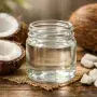 Fresh coconut oil with whole and cracked coconuts in natural light