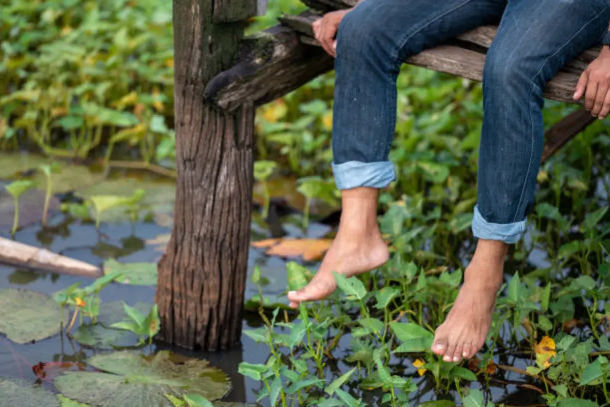 Bare feet resting above calm water, representing reflection and presence
