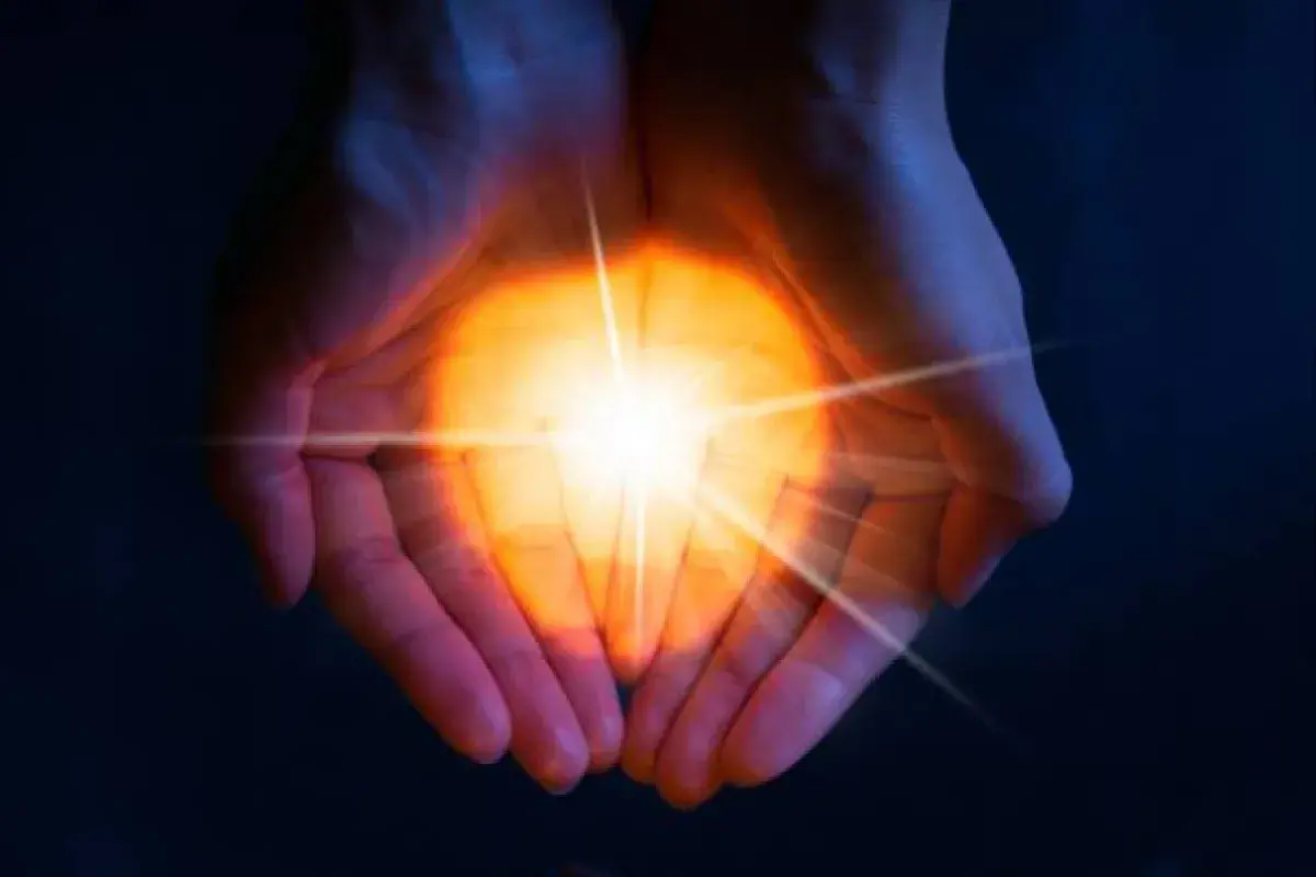 Hands holding light that represents the quiet power of joy.