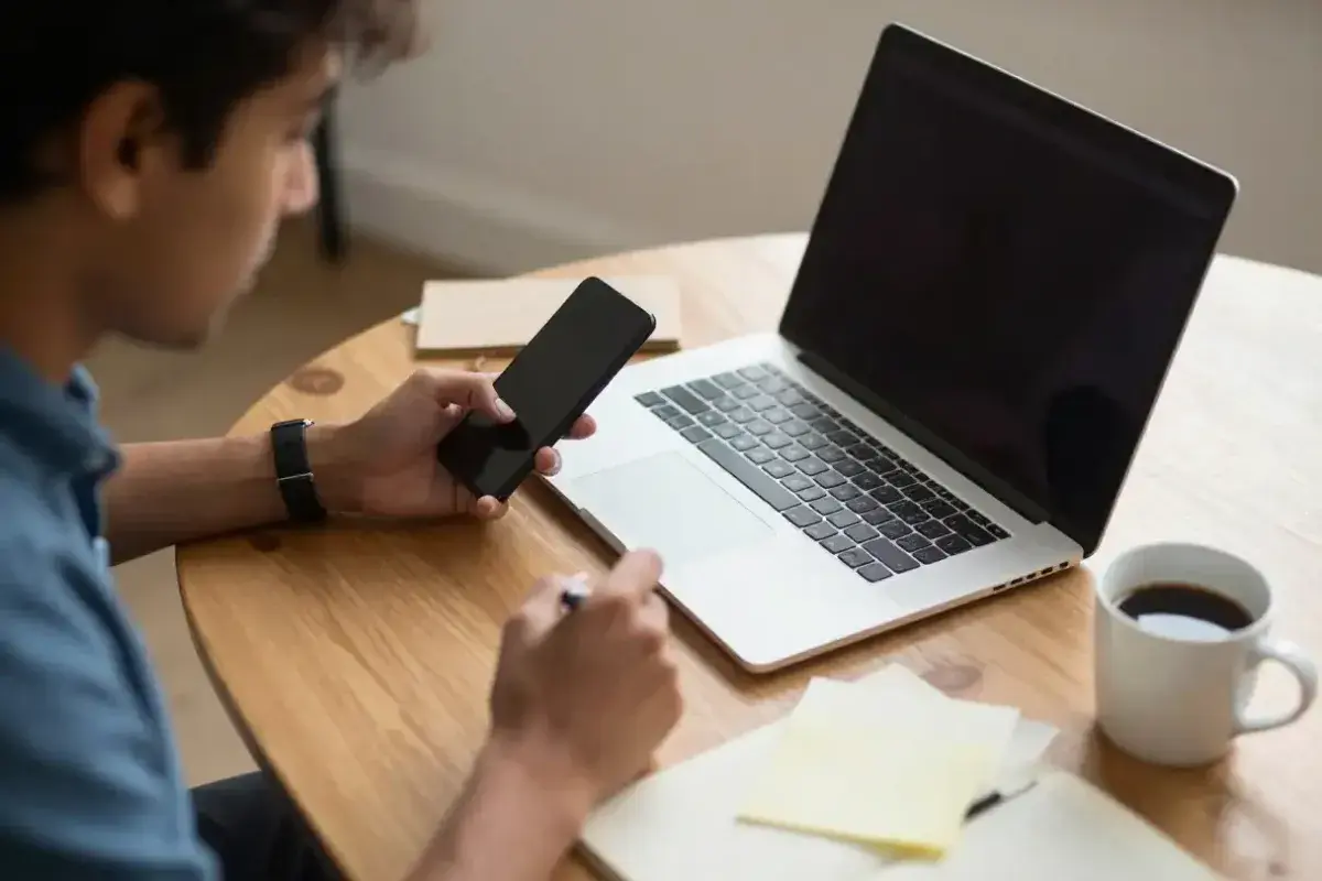 Individual attempting to work while repeatedly checking smartphone