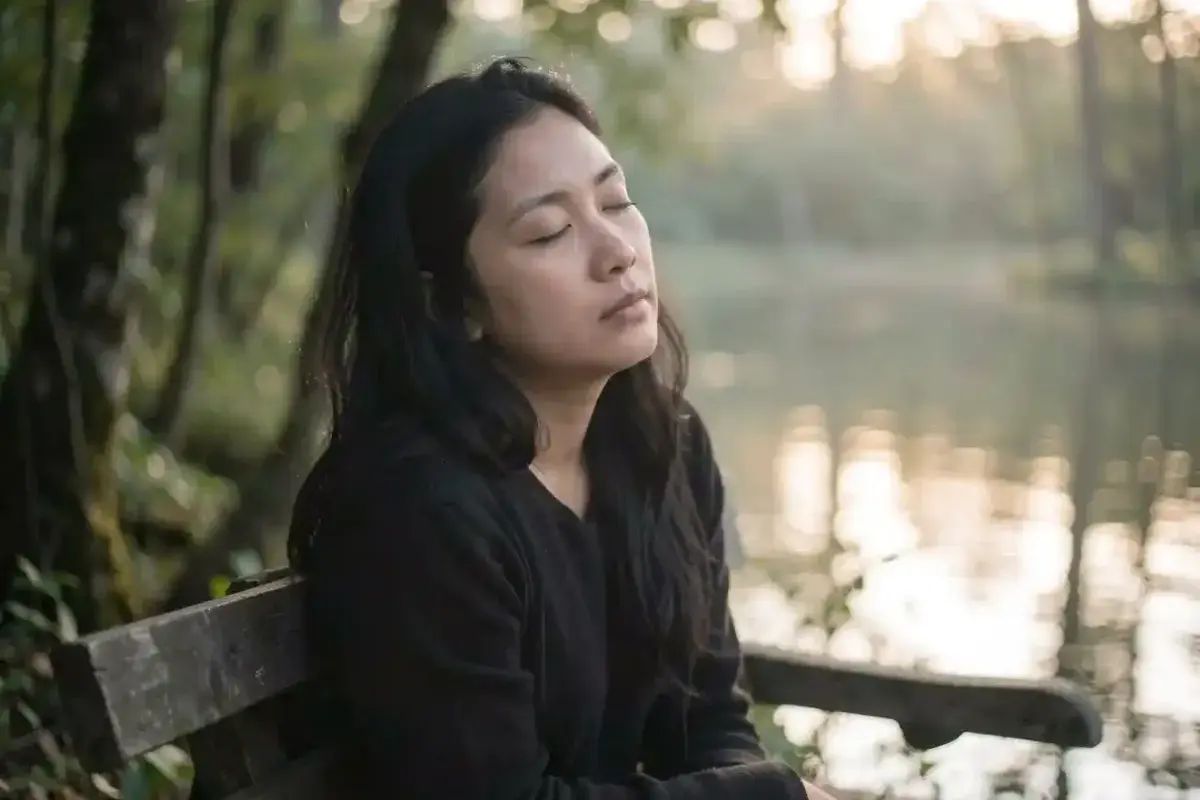 A person sitting in quiet contemplation in nature, symbolizing the spiritual practice of listening with the heart and finding abundance in presence.