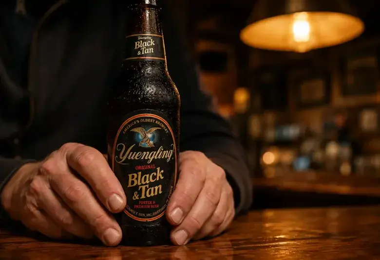 Hands holding a beer bottle in a warm quiet bar
