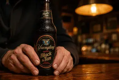 Hands holding a beer bottle in a warm quiet bar