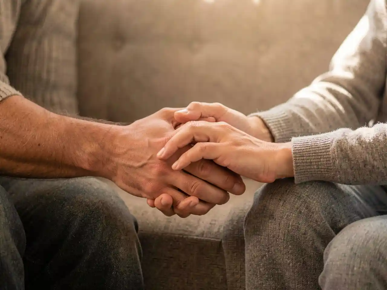 Couple's hands gently holding in a quiet moment of healing and reconnection