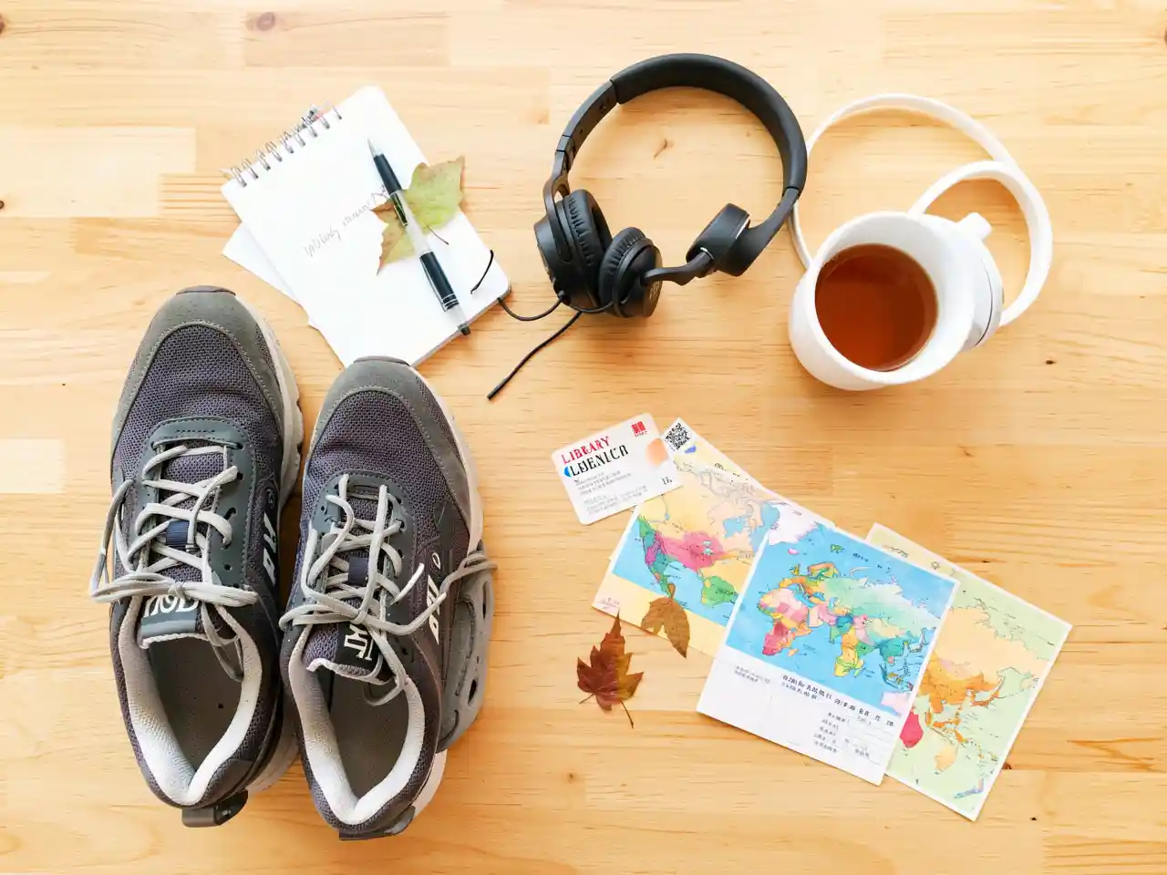 Flatlay of sneakers, notebook, headphones, library card, and small map for weekly adventures