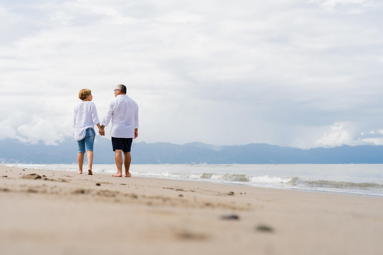 older couple walking by the beach