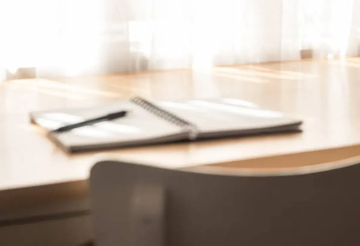 Minimalist desk with a notebook and pen representing reflection and inner stillness.