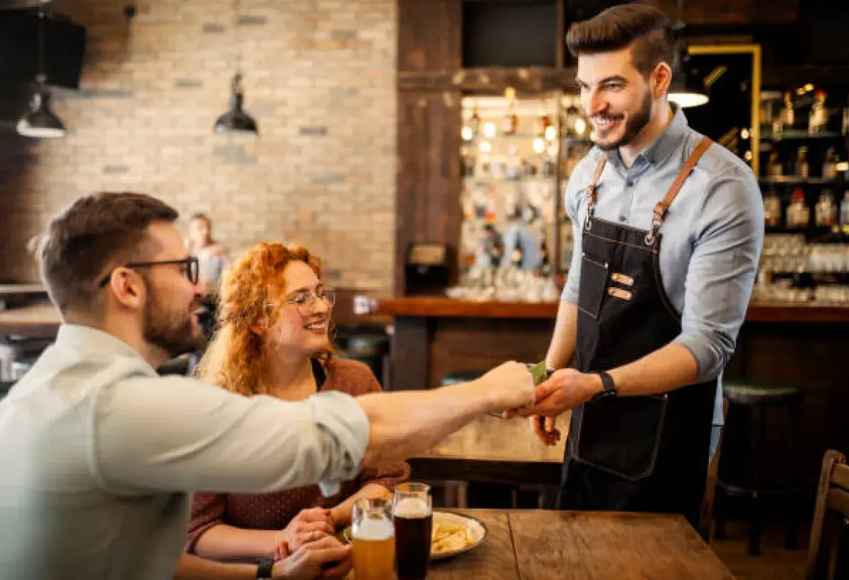 Smiling American waiter receiving a tip at a restaurant.