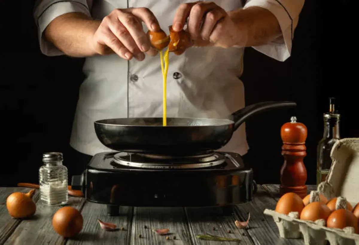 Chef cooking eggs safely in a North American kitchen.
