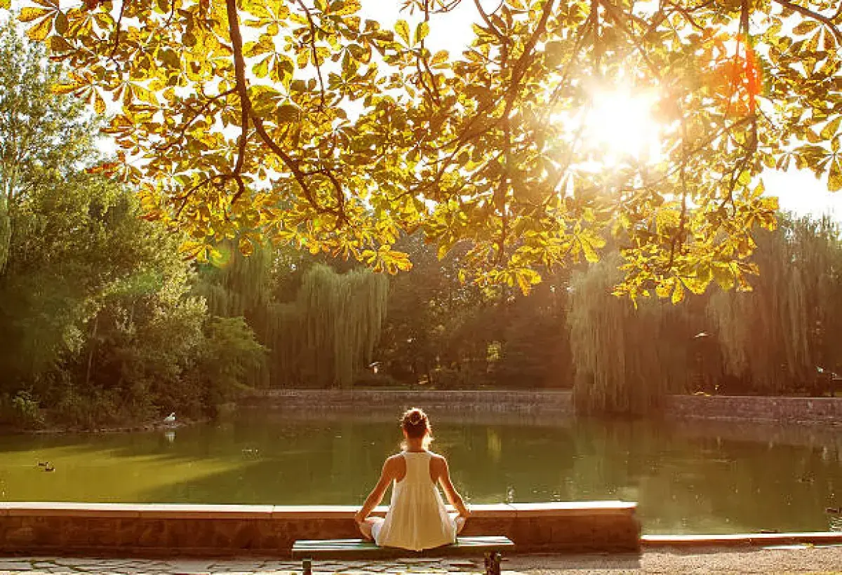 Person meditating on a bench at dawn, symbolizing mindfulness and presence
