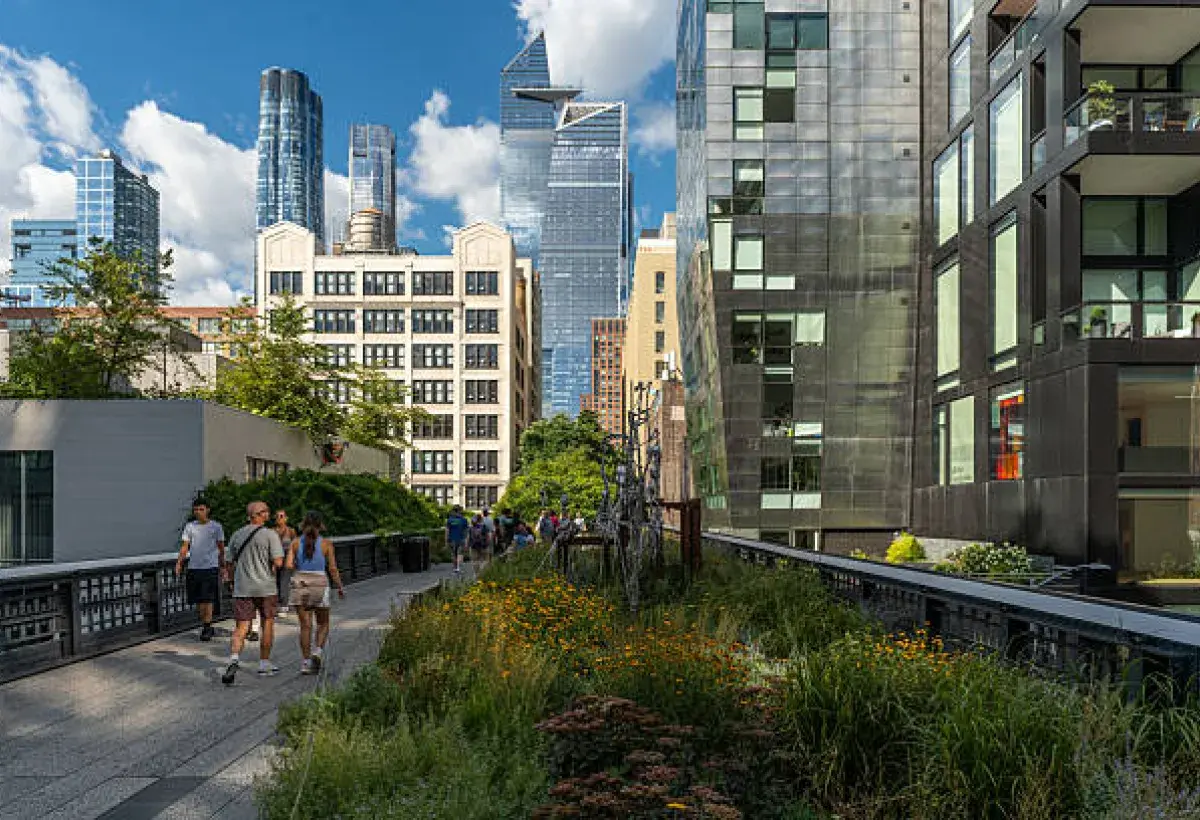 Visitors walking along the High Line park with views of Manhattan buildings