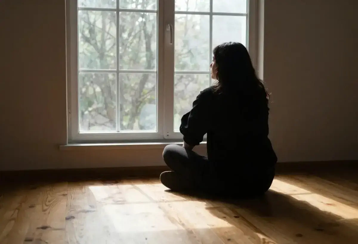  A single figure sitting by a window looking outside, light coming in