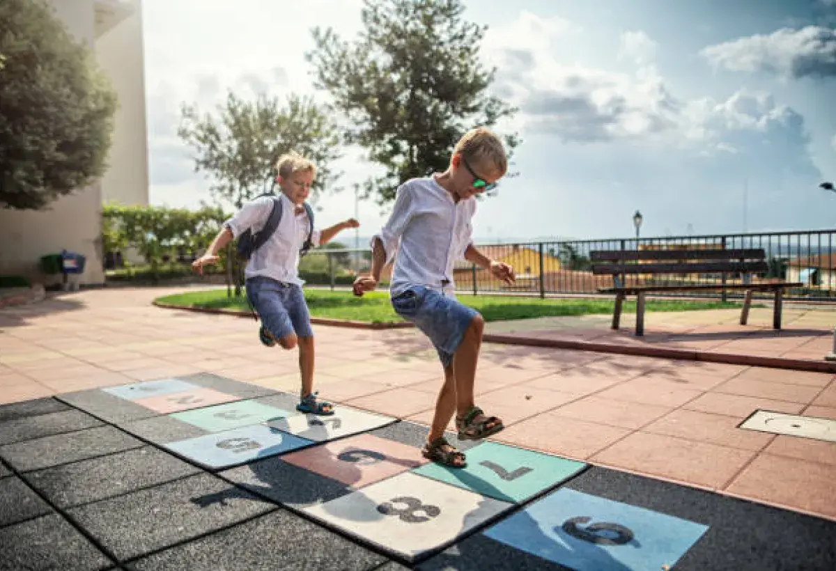 Kids playing hopscotch and running in a playground