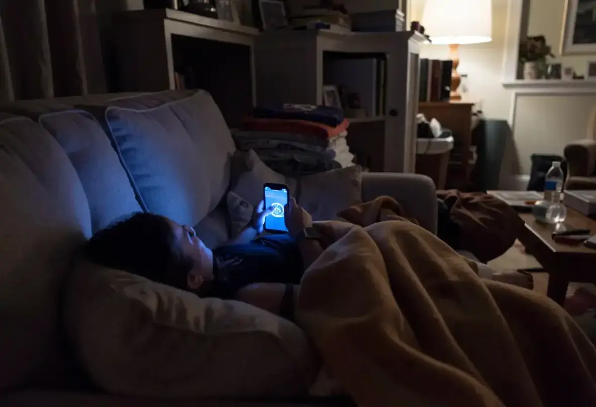 Individual scrolling on smartphone late at night in a dark room