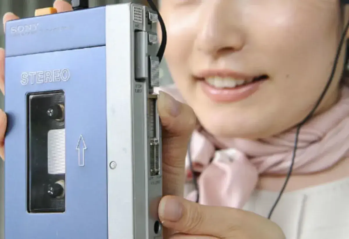 Person using a Sony Walkman with headphones while walking outdoors in 1979