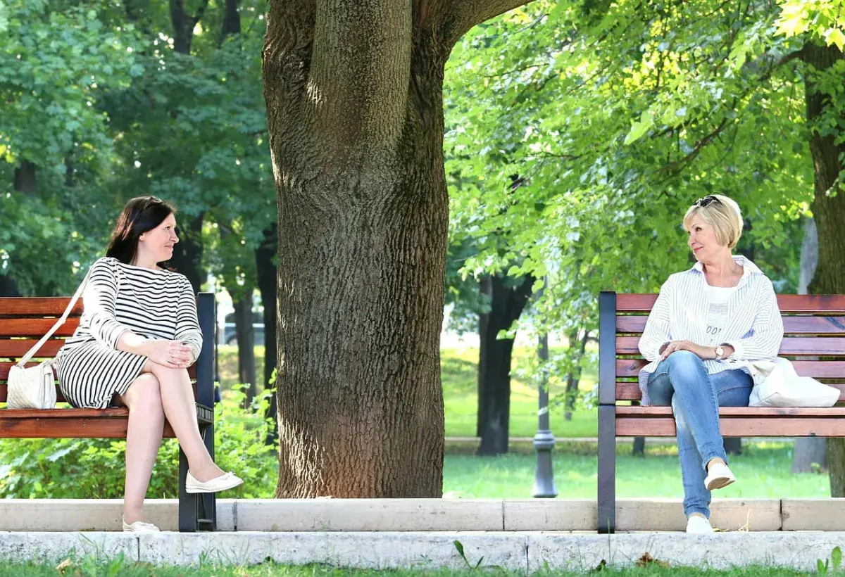 two women sitting with a big tree at the center