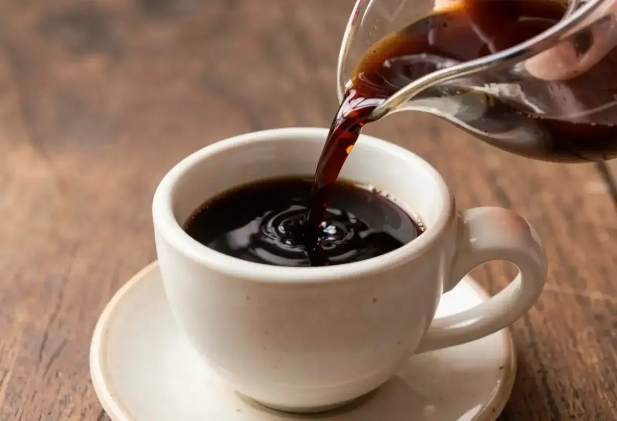 Freshly brewed black tea pouring into ceramic cup