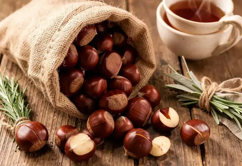A rustic scene of fresh chestnuts in their shells spilling from a sack, with one cut open to reveal the creamy interior, symbolizing their natural, nourishing qualities.