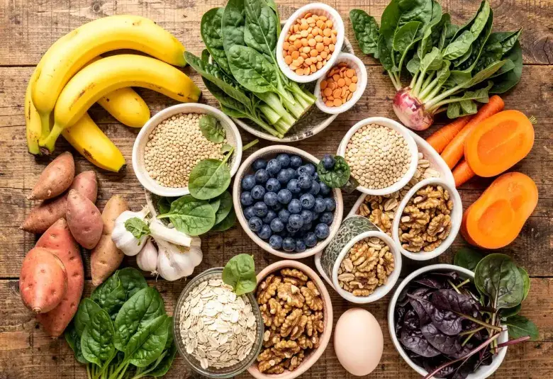 Colorful flatlay of forgotten superfoods including bananas, spinach, lentils, blueberries, and eggs on a rustic table