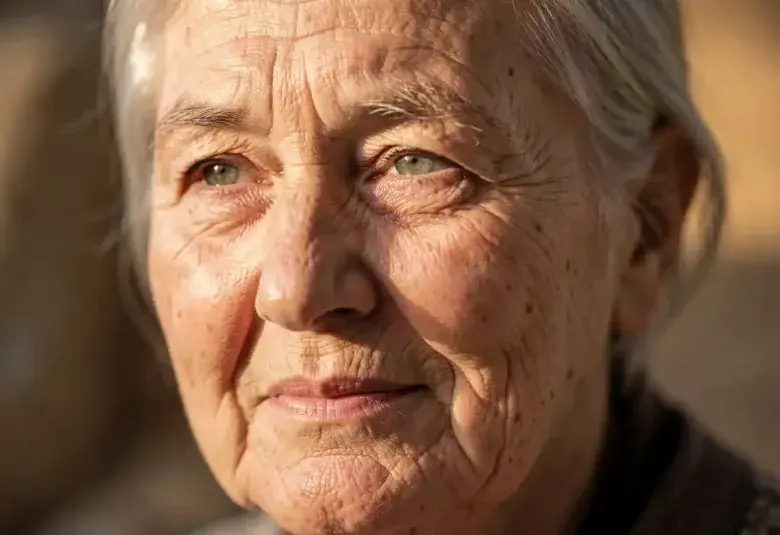 Powerful close-up portrait of an older person's face with warm, artistic lighting, celebrating their resilience, wisdom, and dignity in facing the challenges of aging