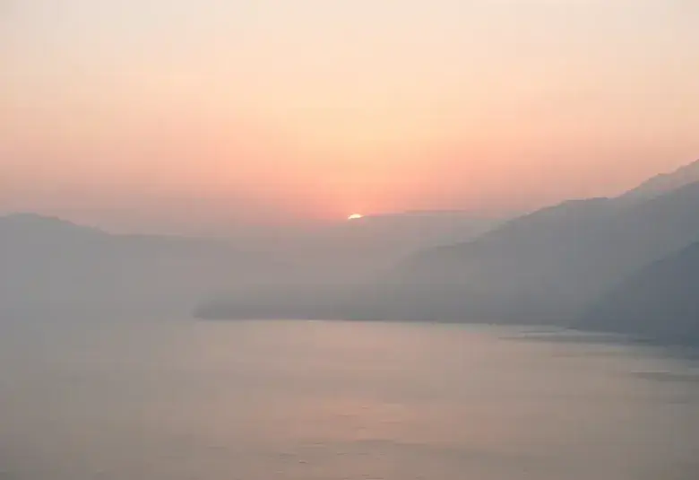 Serene sunrise over a calm sea or misty mountains, representing peace and God's presence