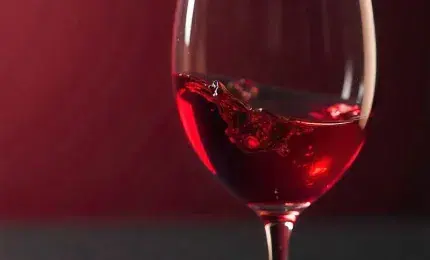 swirling red wine in clear glass on wooden table
