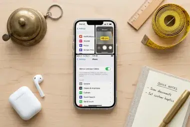 An iPhone surrounded by a notepad, measuring tape, and bell, symbolizing the hidden, practical features that improve daily life.