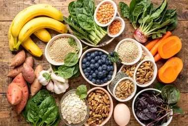 Colorful flatlay of forgotten superfoods including bananas, spinach, lentils, blueberries, and eggs on a rustic table