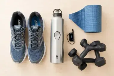 Flatlay of active lifestyle gear including shoes, water bottle, fitness tracker, and dumbbells