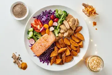 Top-down flat-lay of a vibrant, nutrient-dense plate divided into colorful vegetables, quality protein, and smart carbs, with small dishes of nutritional boosters