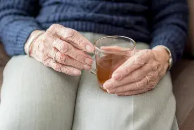old hand holding a cup of tea