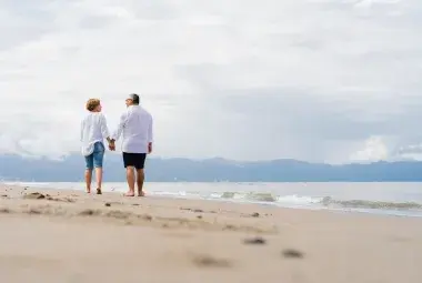 older couple walking by the beach